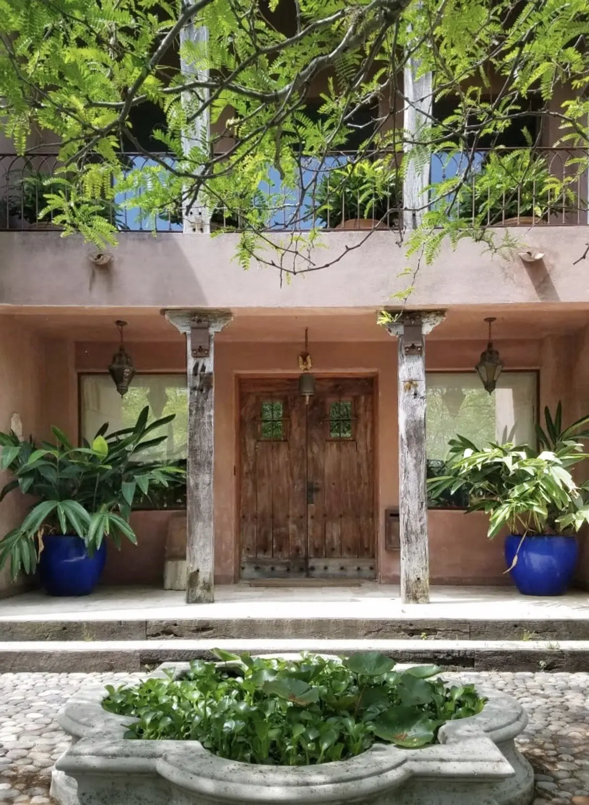 Fachada mediterrânea com portas de madeira rústica e vegetação exuberante — projeto Laguna del Sol, por Estudio Moreto Bensusan, em Tigre