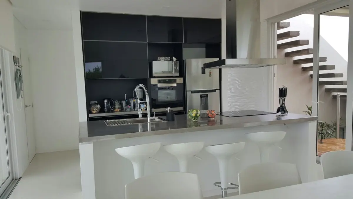 Cocina moderna integrada con isla y barra, estufas de acero inox — proyecto Costa Esmeralda, por Cuello Selva, en Costa Esmeralda