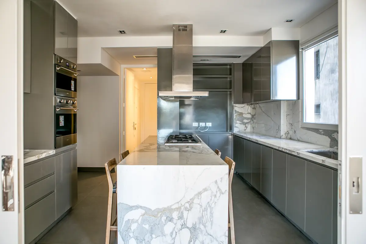 Cocina moderna con isla de mármol y muebles grises — proyecto Lafinur, por Estudio Magrane, en CABA
