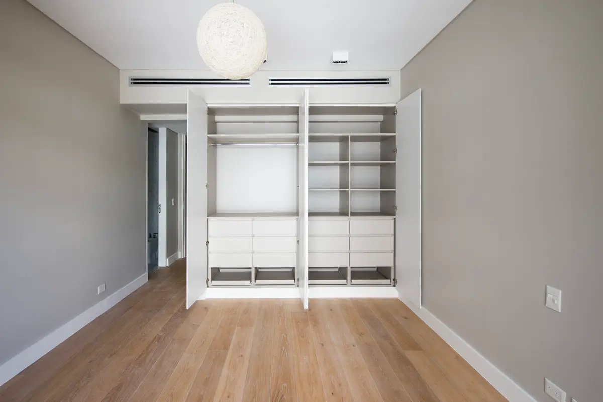 Dormitorio moderno con vestidor abierto de madera y piso de parquet — proyecto Lafinur, por Estudio Magrane, en CABA