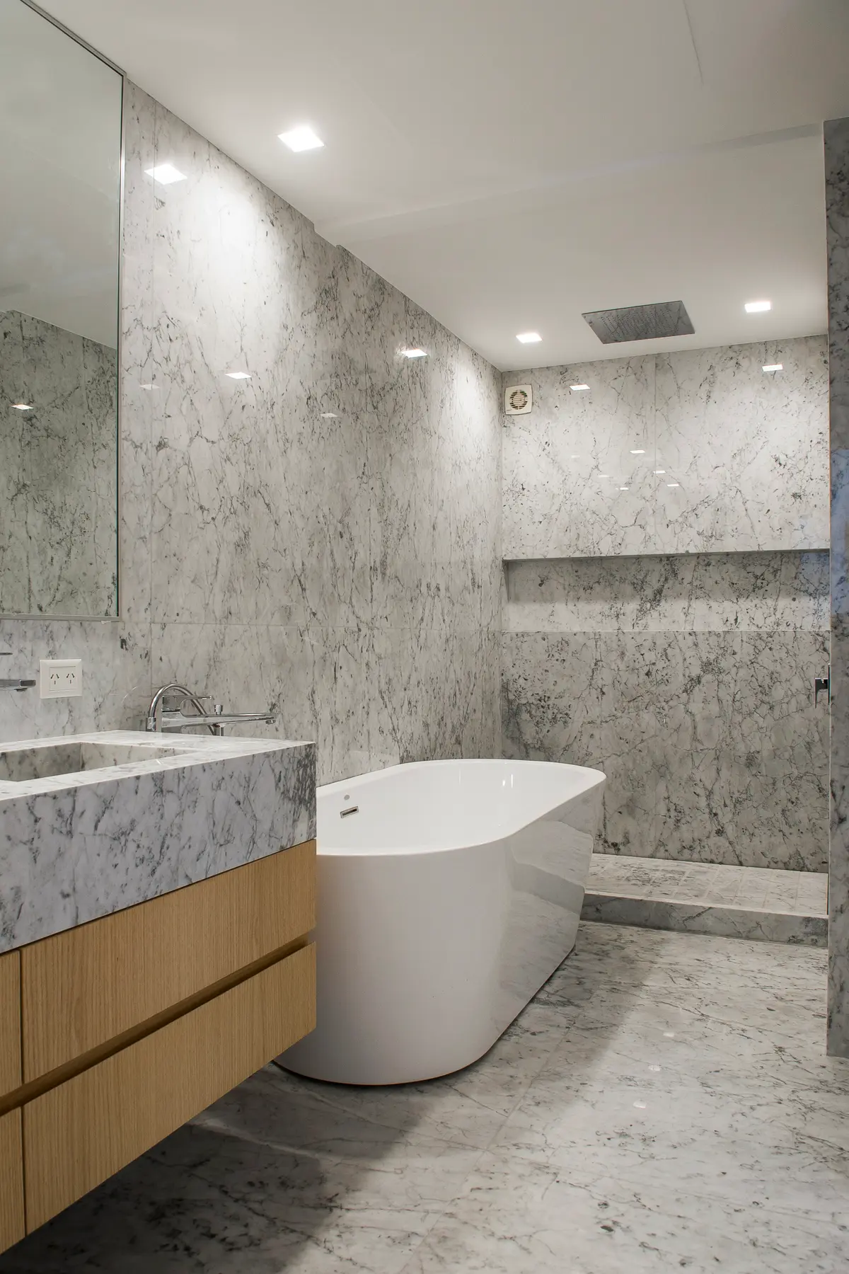 Banheiro moderno com revestimento de mármore cinza e banheira freestanding — projeto Lafinur, por Estudio Magrane, em CABA
