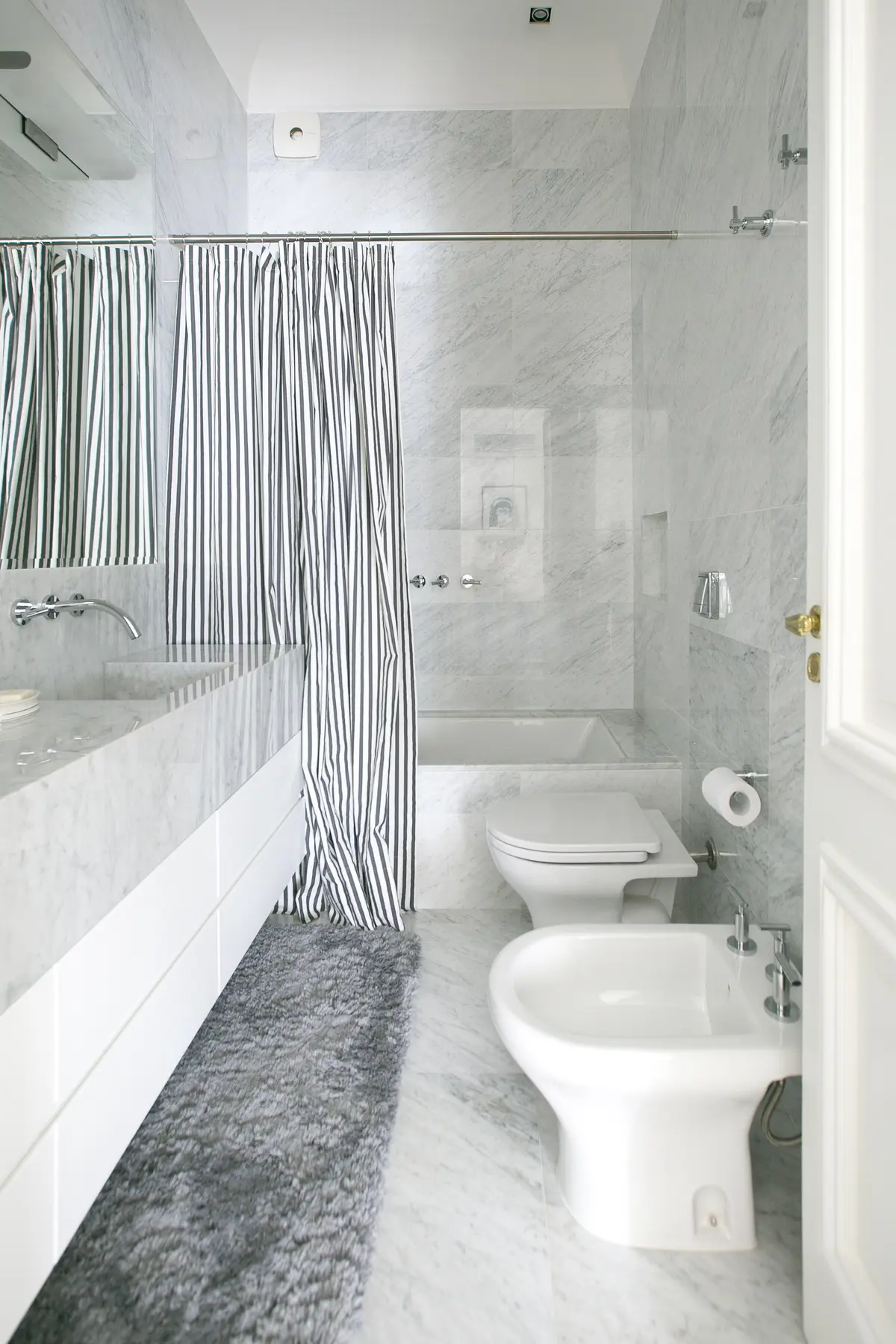 Baño moderno con mármol blanco, ducha y bidet — proyecto Libertador y Salguero, por Estudio Magrane, en CABA