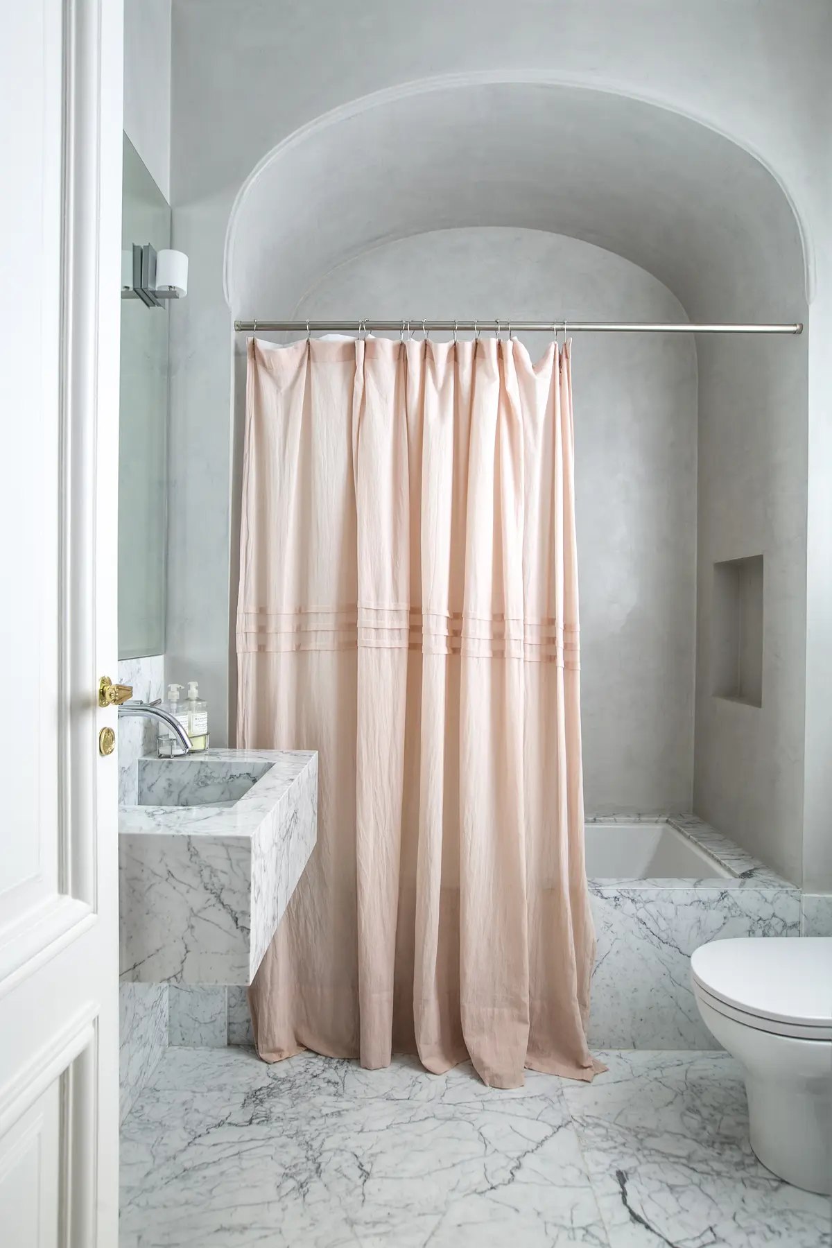 Baño moderno con revestimientos de mármol y cortina de ducha beige — proyecto Libertador y Salguero, por Estudio Magrane, en CABA