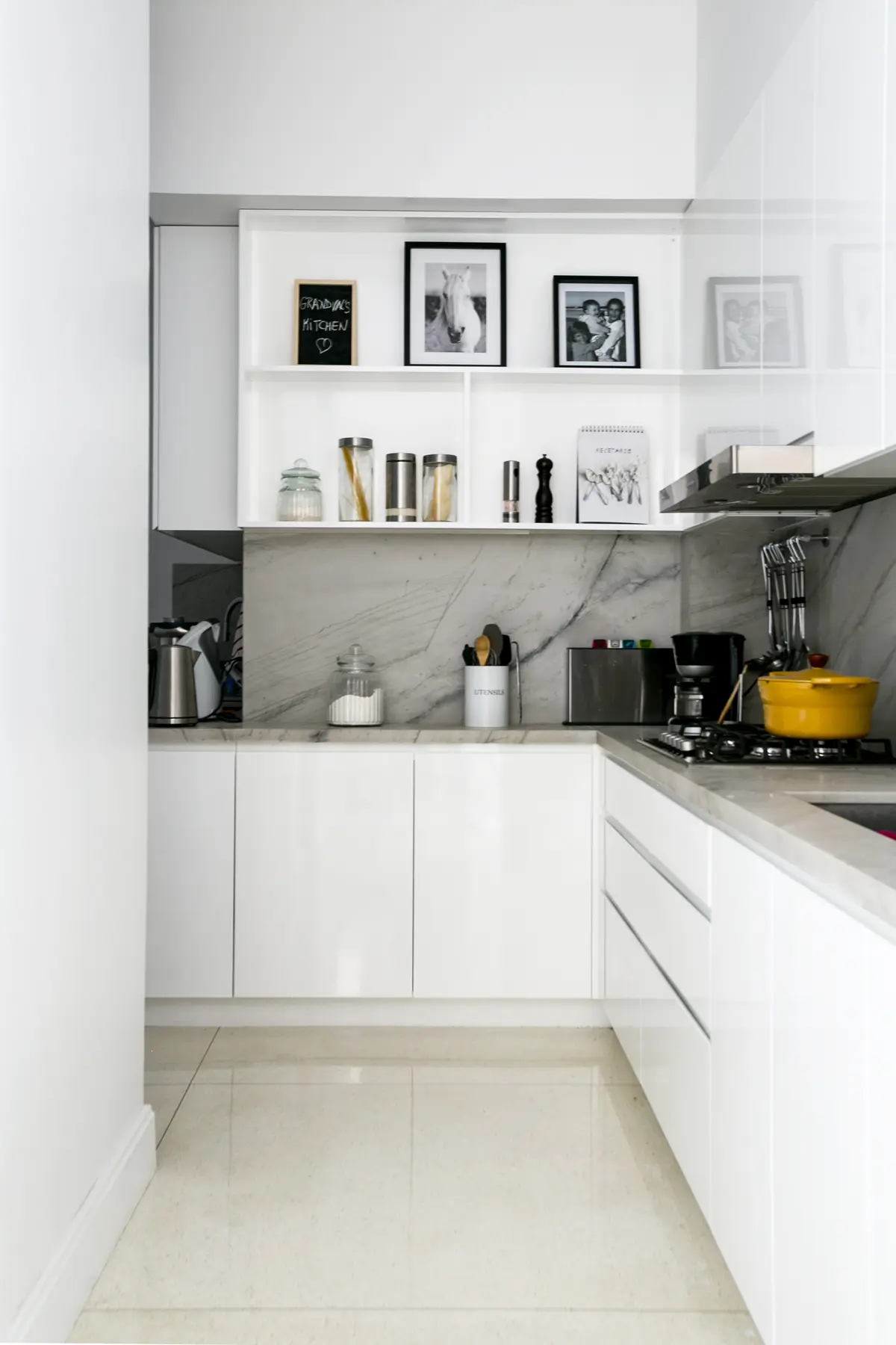 Cocina moderna con estantes flotantes blancos y mesada de mármol — proyecto Libertador y Salguero, por Estudio Magrane, en CABA
