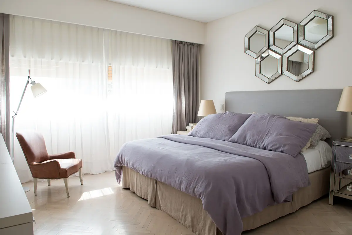 dormitorio moderno con cama grande y sillón tapizado beige — proyecto San Martín de Tours, por Estudio Magrane, en CABA