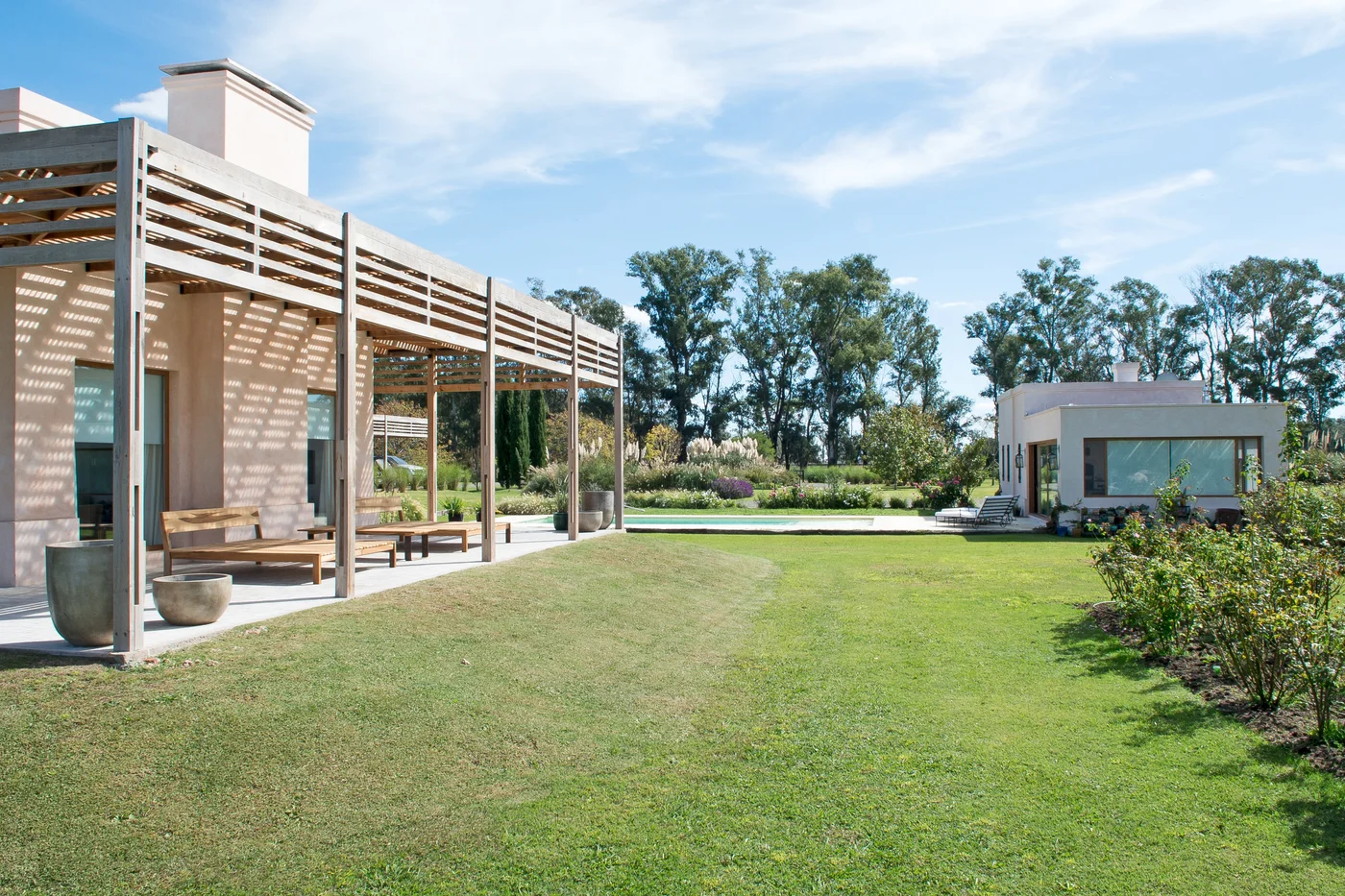 Jardín de casa moderna con galería de pérgola de madera y pileta