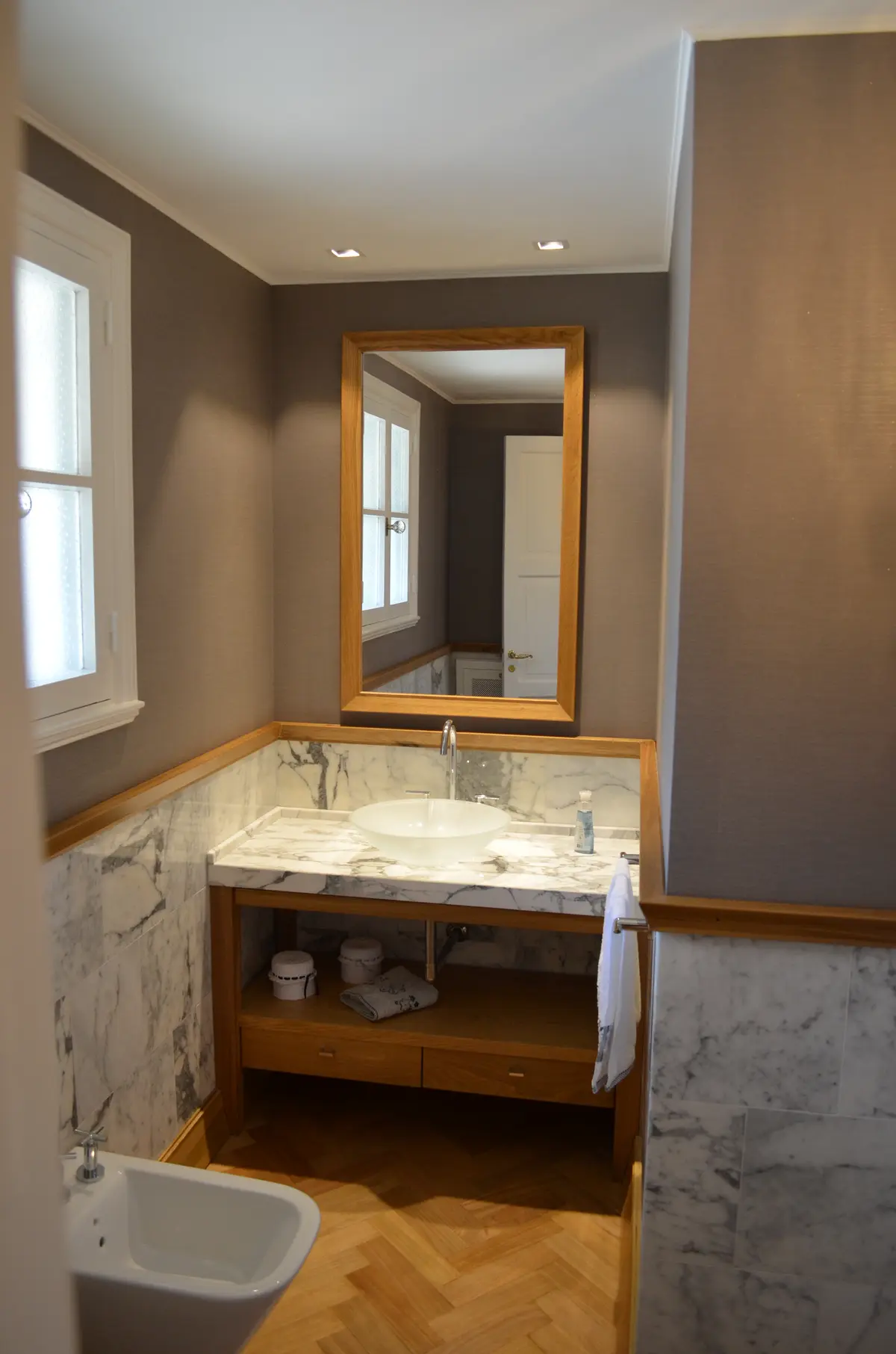 Baño moderno con vanitory de mármol y suelo de madera — proyecto Casa en Barrio El Jockey - San Isidro, por GEN STUDIO  COMOTTO - SOMMER , en San Isidro