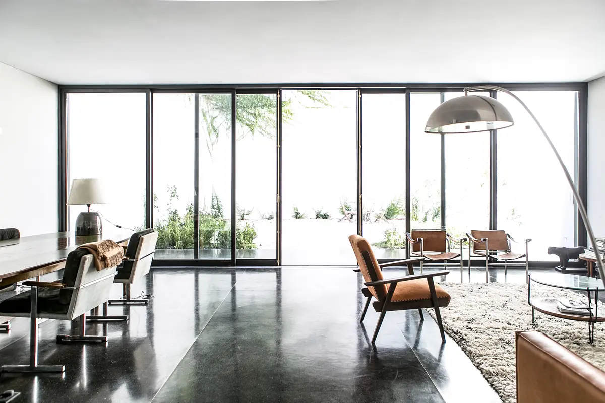 Sala moderna com grandes janelas e poltronas de couro marrons — projeto Belgrano, por Estudio Magrane, em Belgrano