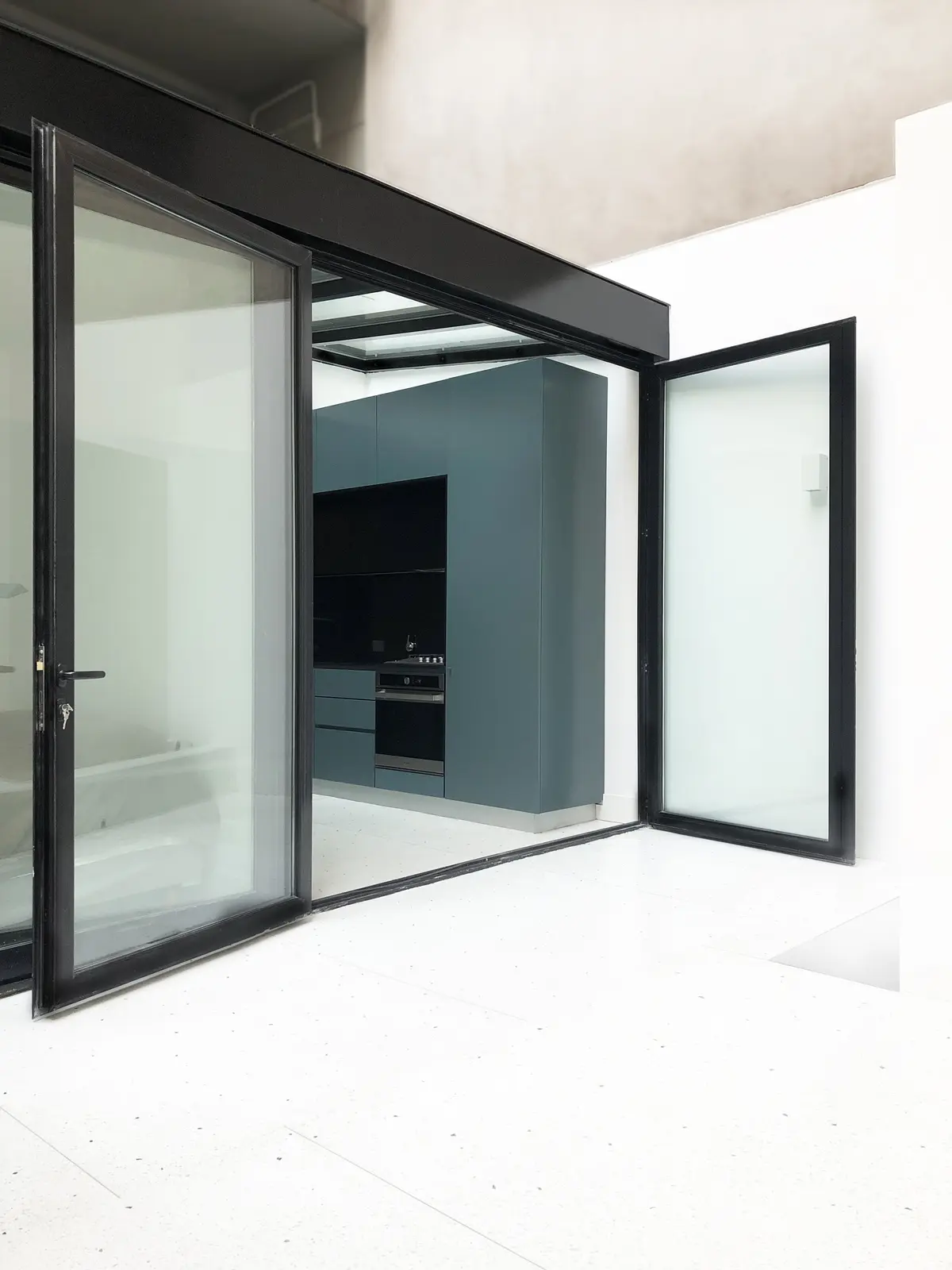 Cocina moderna minimalista con puertas de vidrio plegables y gabinetes azules — proyecto Luis María Campos , por Estudio MMS , en CABA