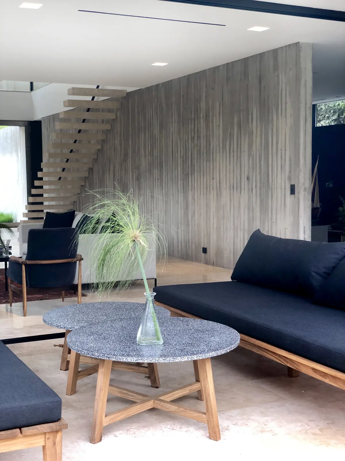 Sala de estar moderna com parede de concreto aparente e escada flutuante — projeto Las Lomas, por Estudio MMS, em San Isidro