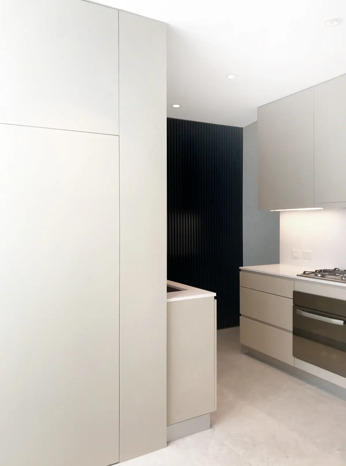 Cocina moderna minimalista con muebles blancos y pared de lamas negras — proyecto Scalabrini Ortiz, por Estudio MMS , en CABA