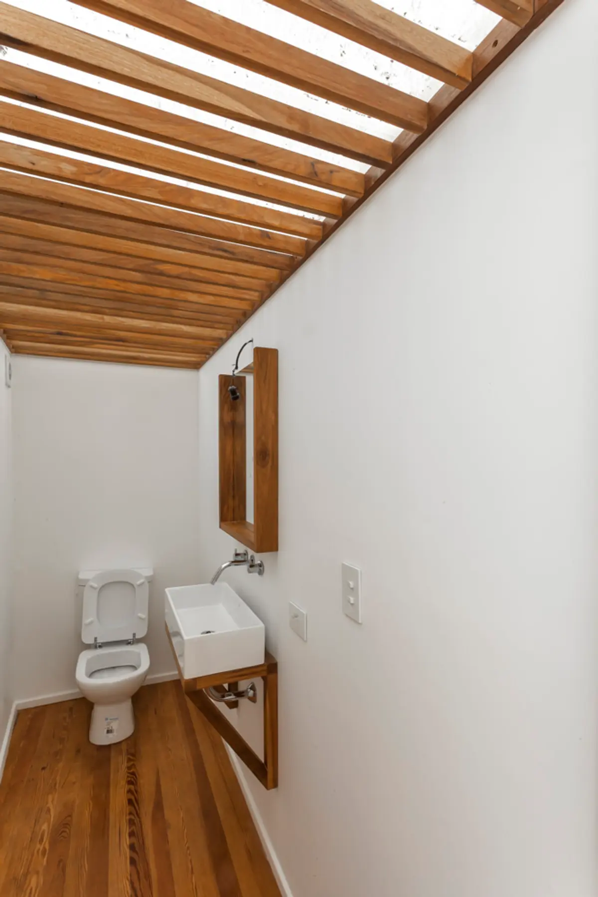 Banheiro estreito com teto de ripas de madeira e luz natural — projeto PH Tamborini, por ariana werber arquitecta, em Núñez