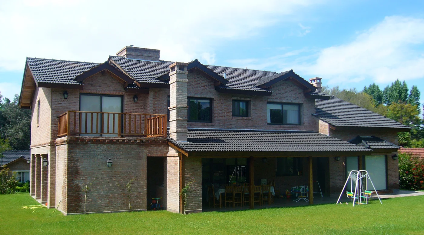 Fachada de casa moderna de ladrillos con pérgola y patio