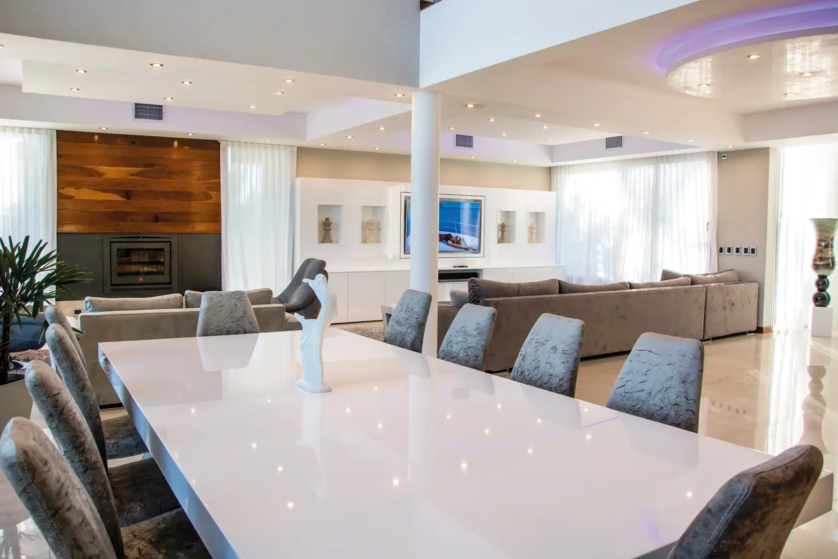 Living comedor moderno con paredes de madera y ventanales amplios — proyecto La Reserva Cardales I, por ARQCONS, en Los Cardales