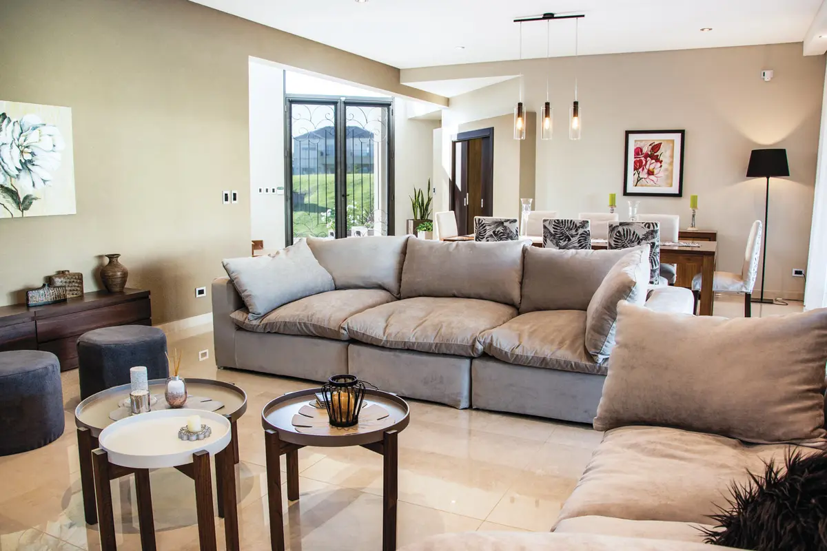 Living moderno con sofá curvo modular y arte abstracto — proyecto Casa Reserva Cardales II, por ARQCONS, en Los Cardales