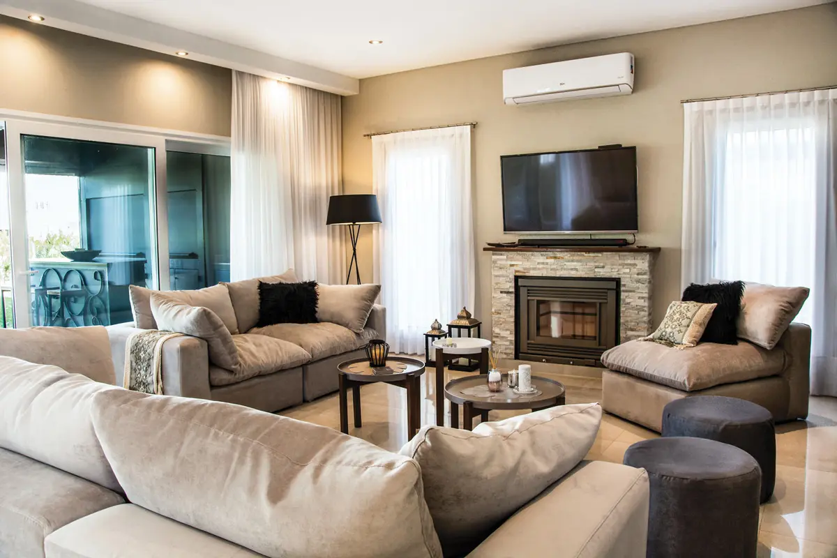 Living moderno con sofá curvo y chimenea de piedra — proyecto Casa Reserva Cardales II, por ARQCONS, en Los Cardales