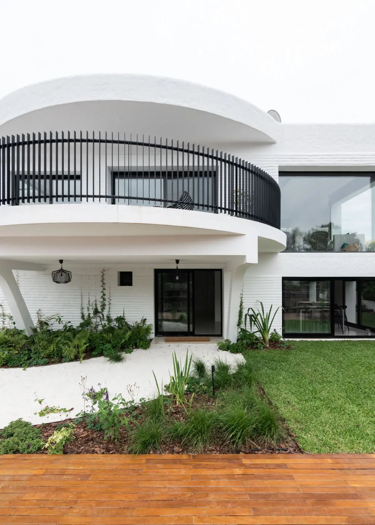 Fachada moderna branca com varanda curva e jardim exuberante — projeto Boating I, por Estudio Arq. Ana M. Carrera, em Boating Club