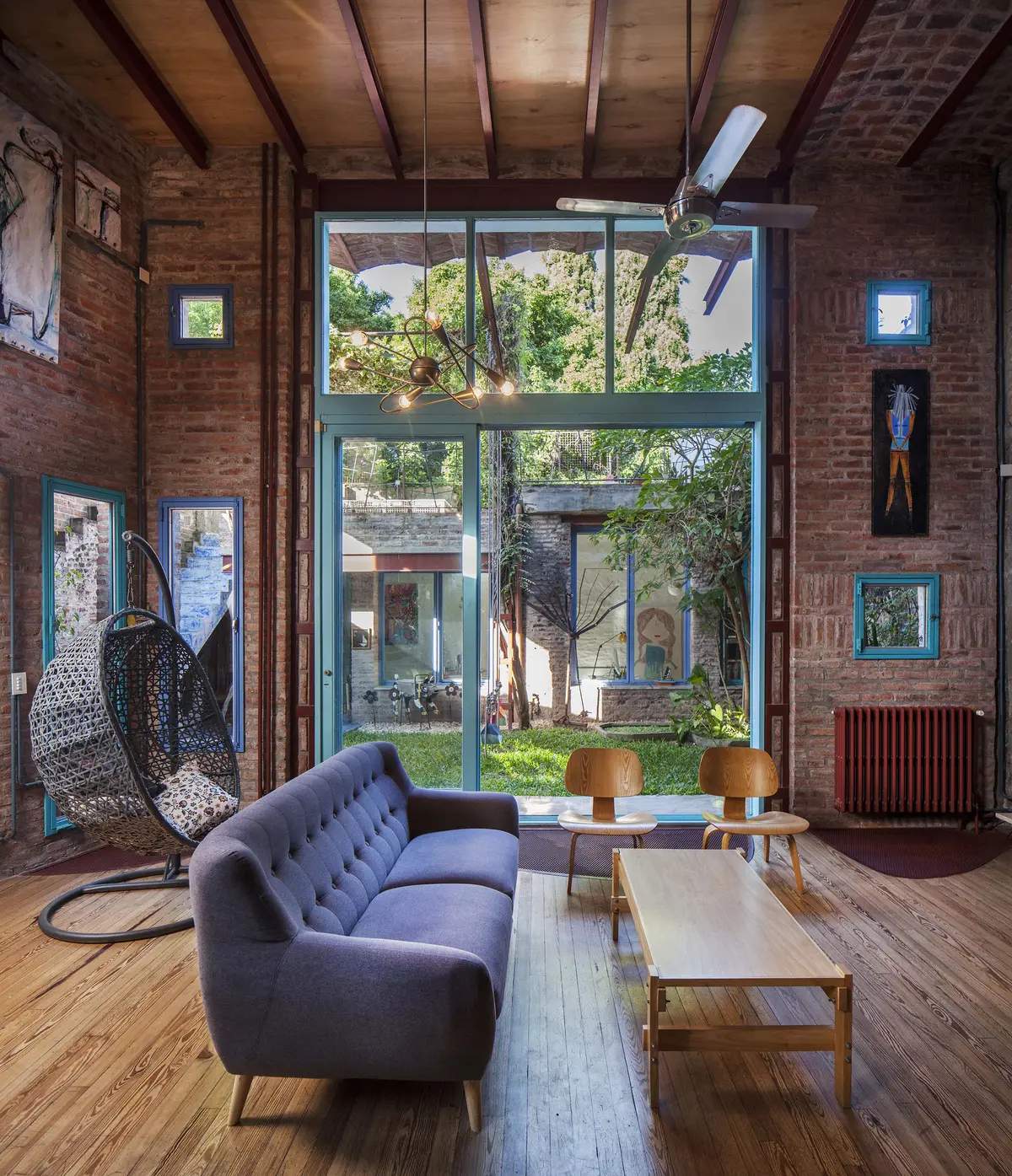 Sala com tijolo aparente, sofá azul e cadeira suspensa — projeto Casa Warnes, por Silvia Soqueff, em CABA