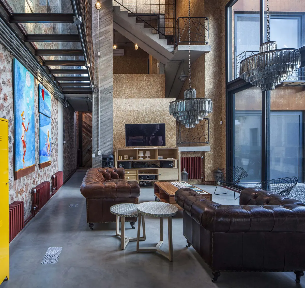 Sala industrial com sofás chesterfield e pé direito duplo — projeto Casa Lavalle, por Silvia Soqueff, em CABA