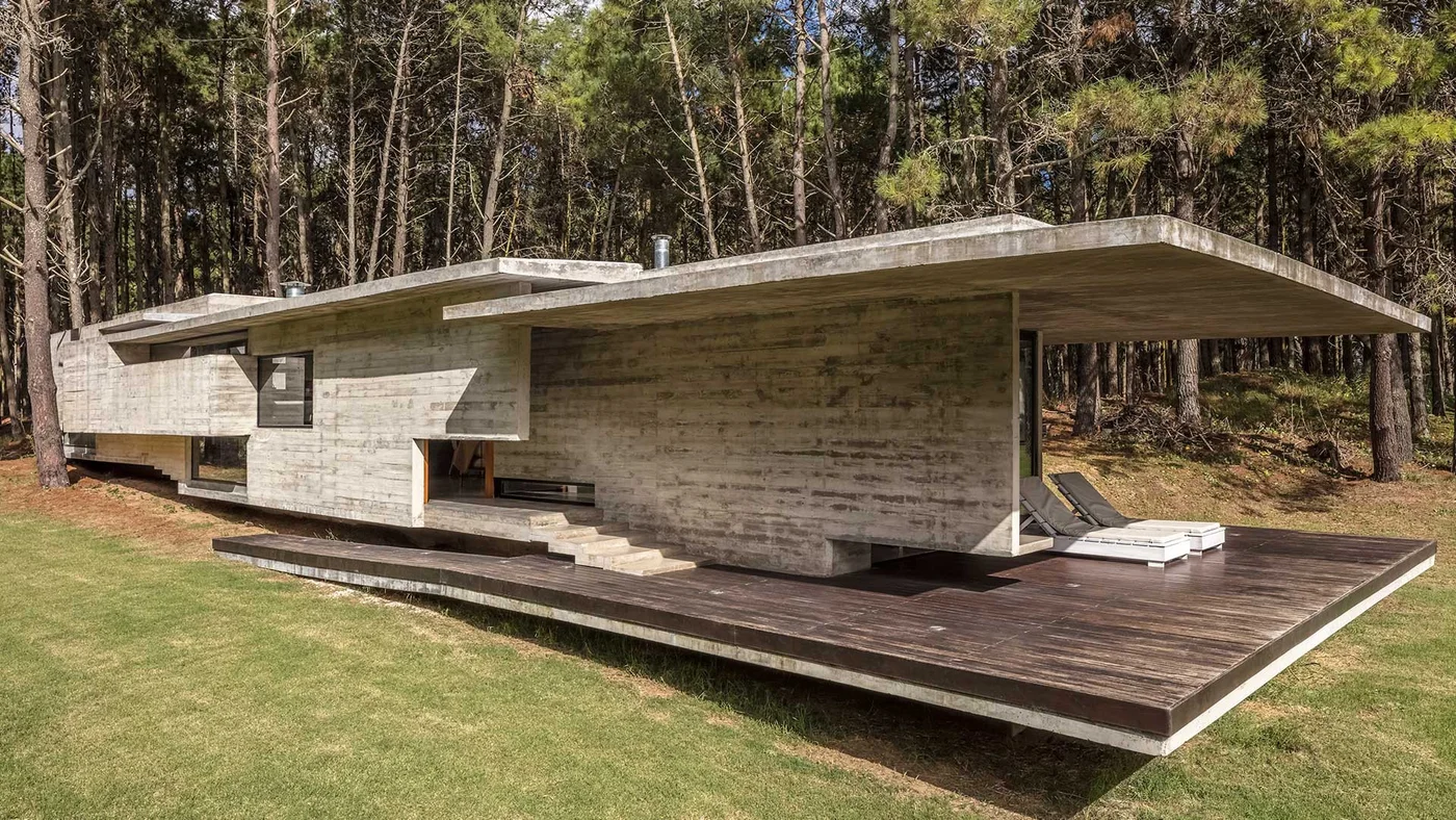 Casa brutalista moderna integrada al bosque con deck de madera