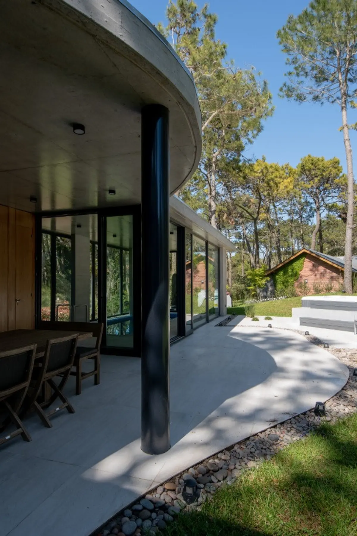 Arquitetura moderna com paredes curvas de concreto e vista para a floresta — projeto Casa G y G, por TAVA Coop, em Cariló