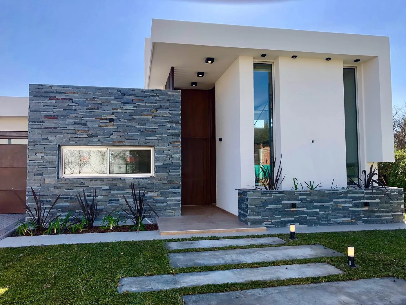 fachada moderna con detalles en piedra apilada y hormigón blanco
