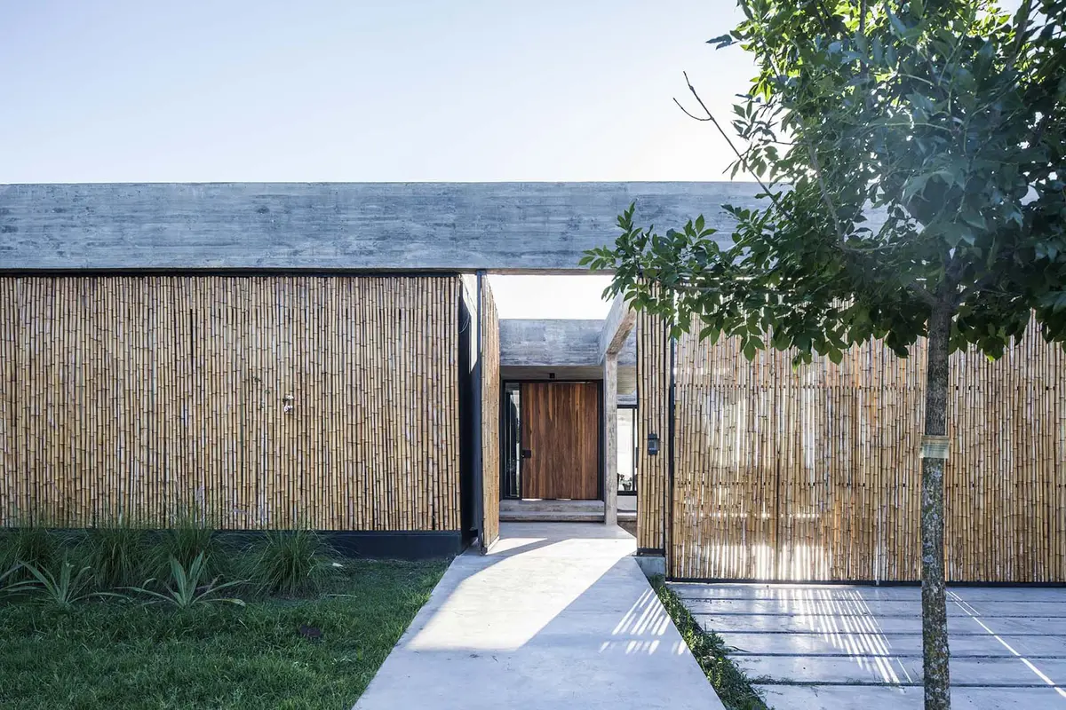 Fachada de casa moderna com revestimento de bambu e concreto — projeto Bamboo House, por Estudio PK