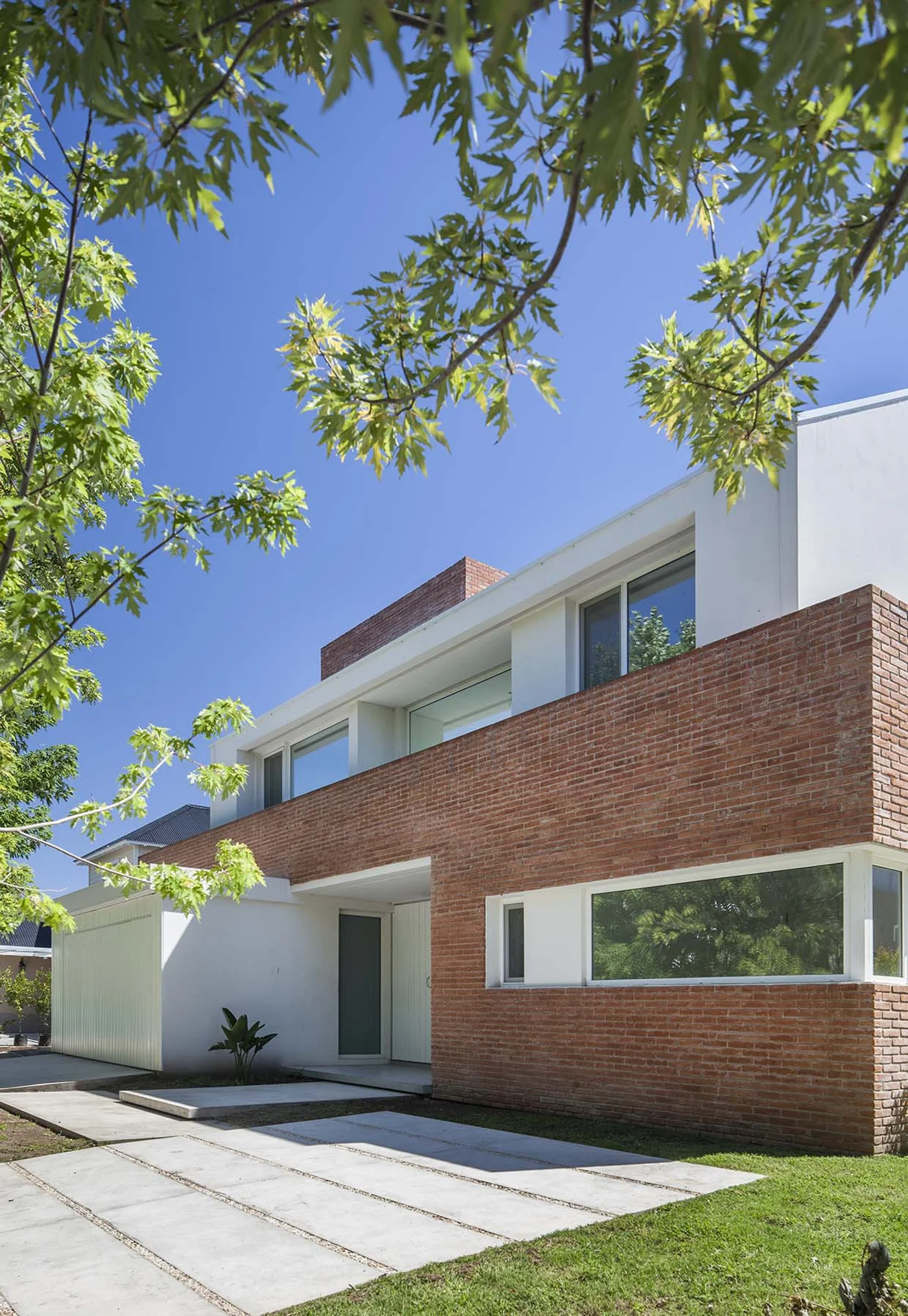 Fachada moderna de ladrillo y blanco con grandes ventanales