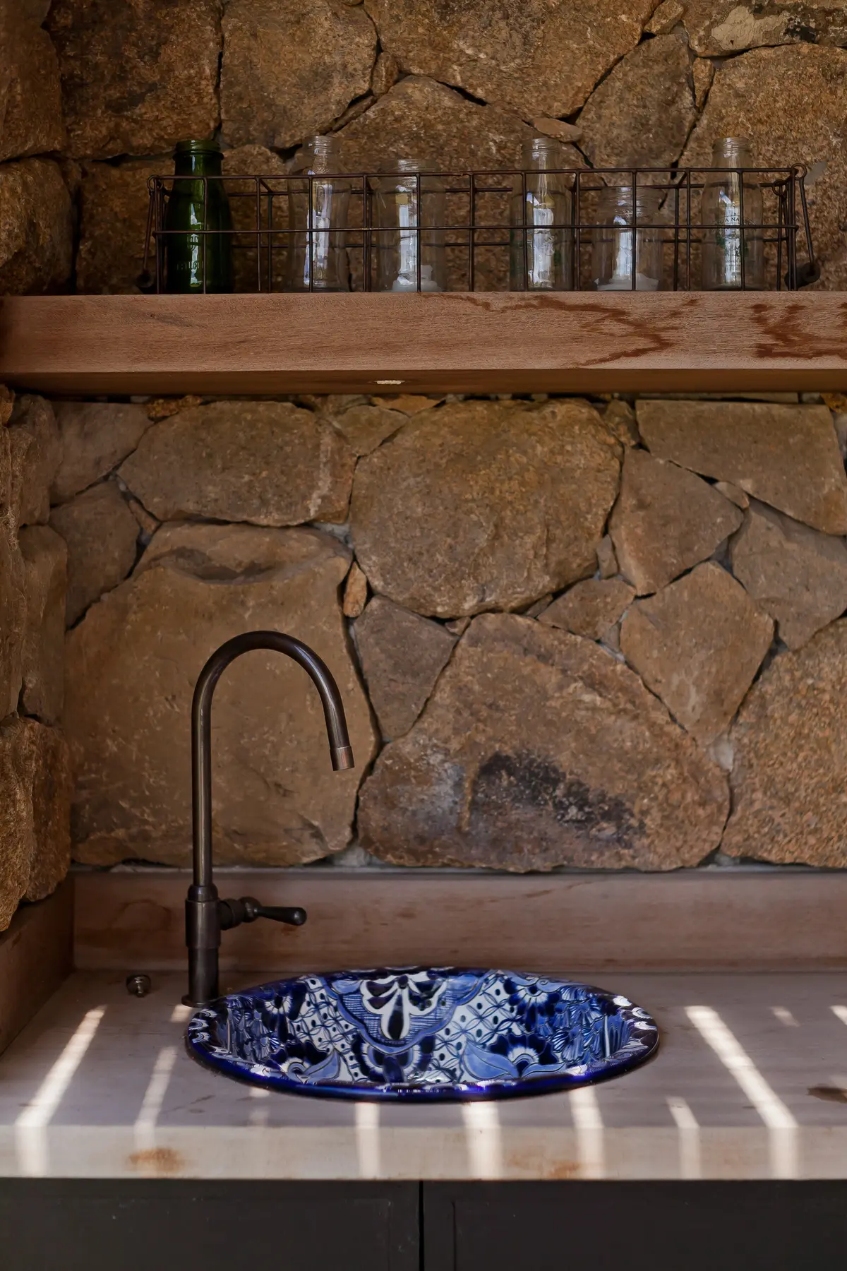 Baño rústico con muro piedra, mesada madera y pileta azul cerámica — proyecto La Tahona, por BAS Y GARCIA , en Canelones Departamento de Canelones