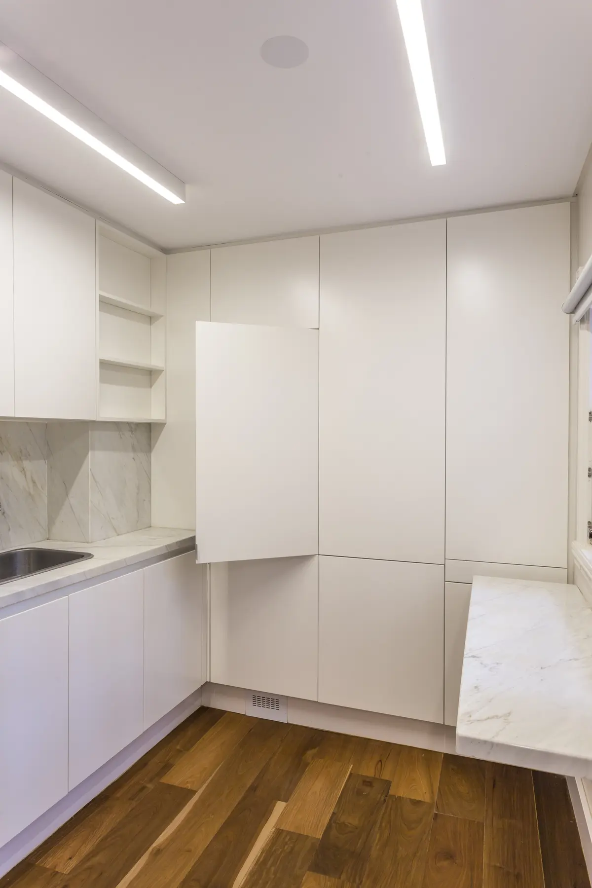 Cocina minimalista blanca con mesada de mármol y piso de madera — proyecto The Classic, por BAS Y GARCIA , en San Isidro