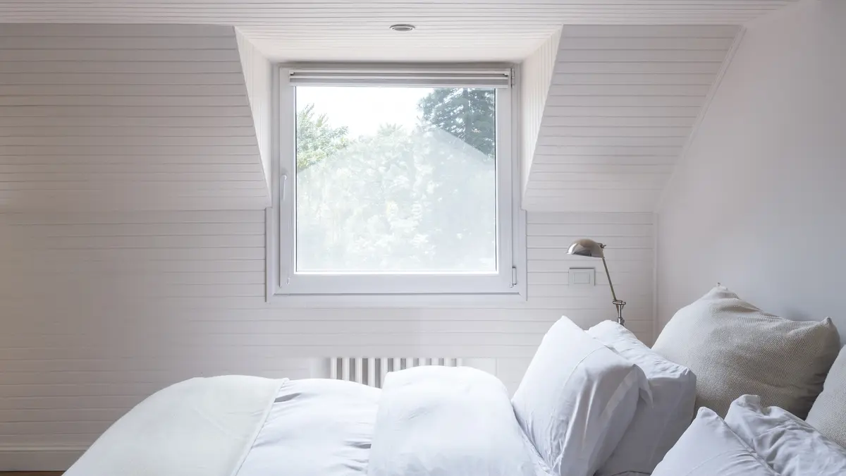 Dormitorio minimalista con ventanal y cama blanca bajo mansarda — proyecto The Classic, por BAS Y GARCIA , en San Isidro