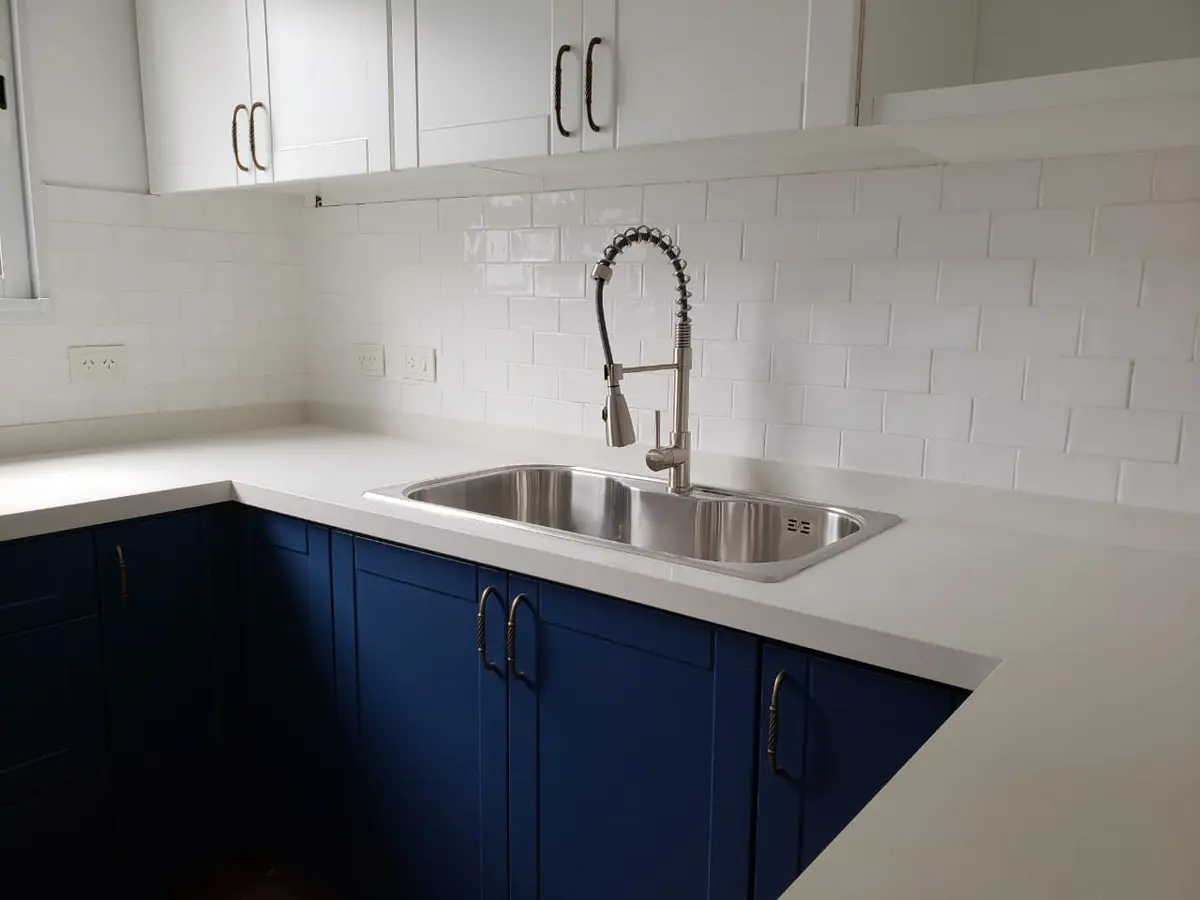 Cocina moderna con muebles azul oscuro, mesada blanca y backsplash de azulejos blancos — proyecto Viamonte, por Biaus Pieres Arquitectura, en CABA