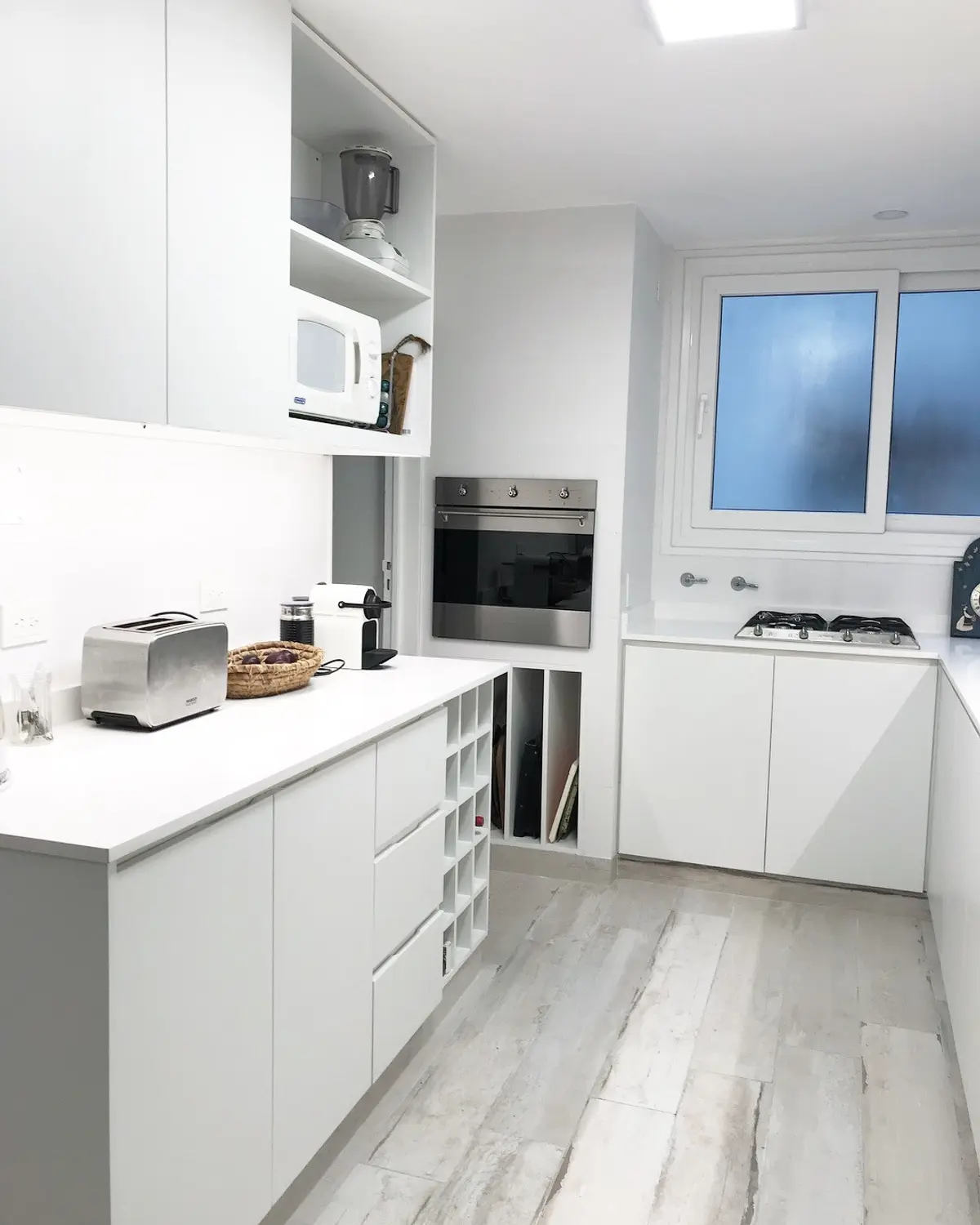 Cocina moderna blanca con mesada de mármol y equipamiento integrado — proyecto Paraná , por Biaus Pieres Arquitectura, en CABA