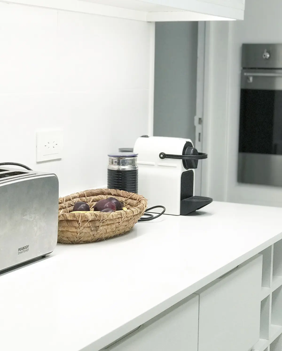 Mesada blanca de cocina moderna con electrodomésticos y cesta decorativa — proyecto Paraná , por Biaus Pieres Arquitectura, en CABA