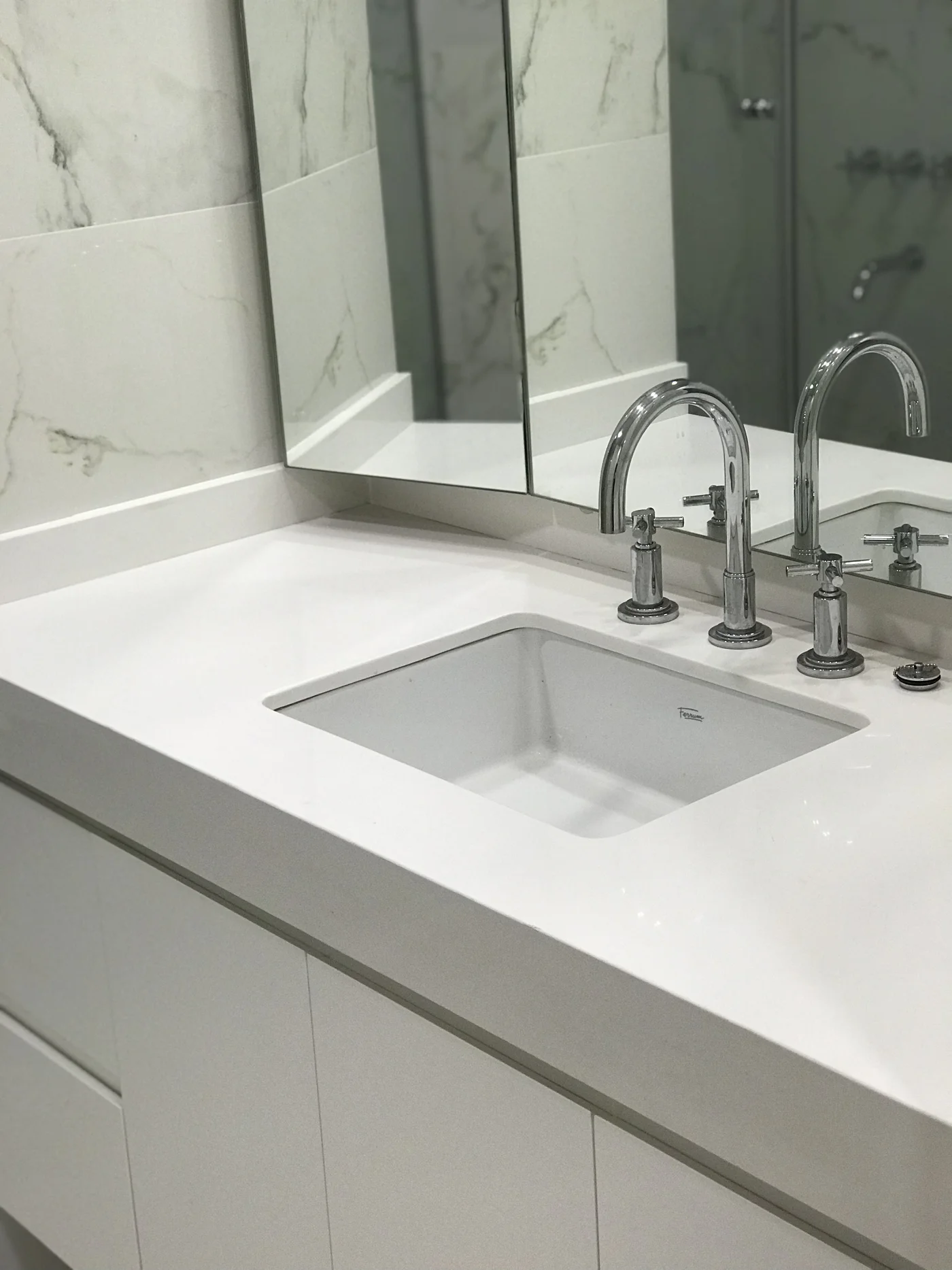 Baño minimalista blanco con mesada de mármol y grifería cromada