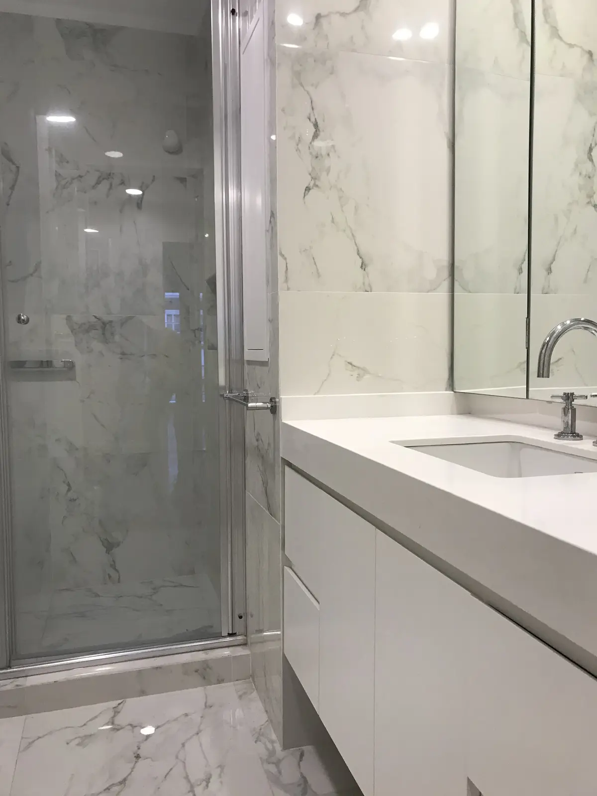 Baño moderno con marmol, ducha cristal y mesada blanca minimalista — proyecto Paraná , por Biaus Pieres Arquitectura, en CABA