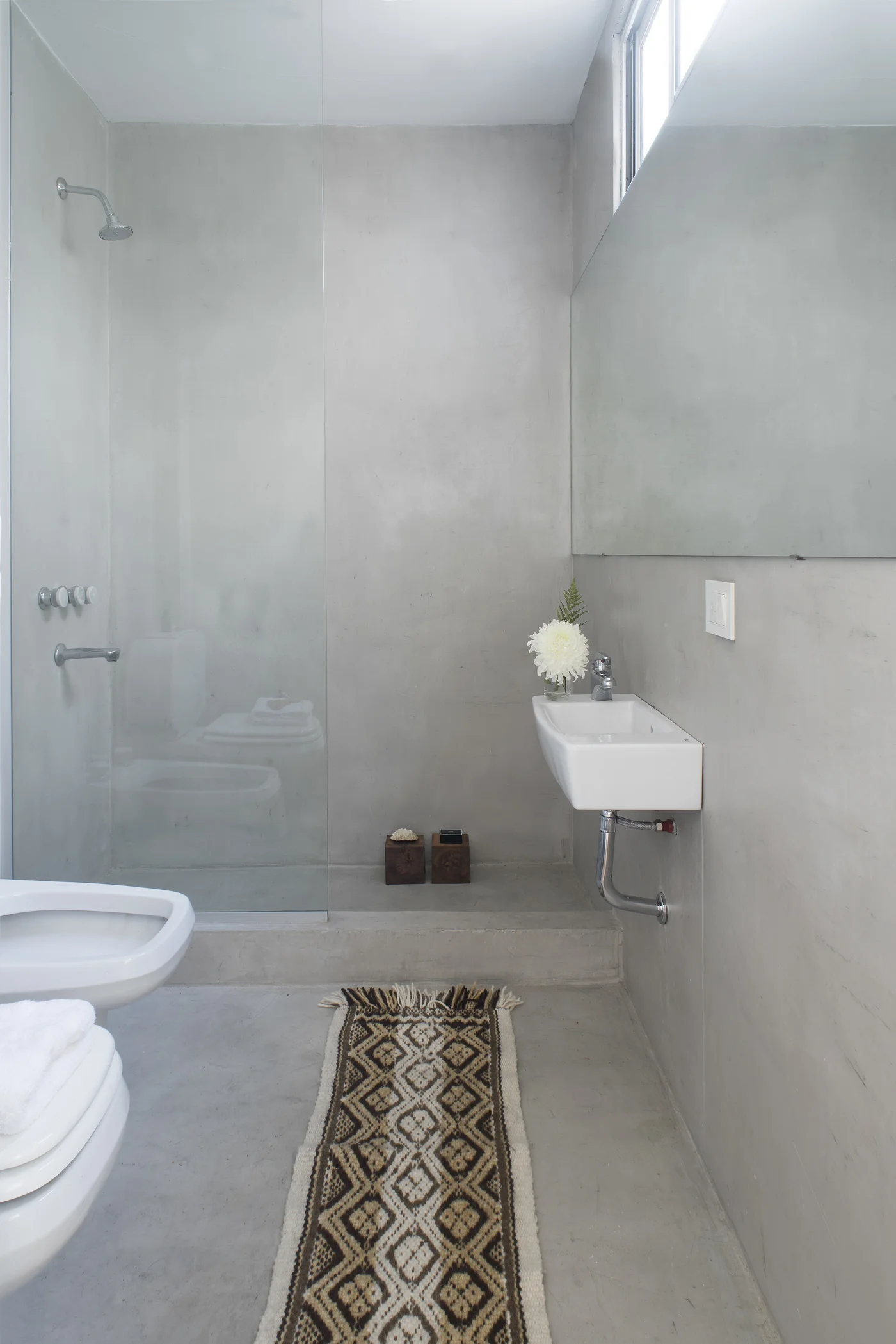 Baño minimalista gris con ducha empotrada y lavatorio suspendido
