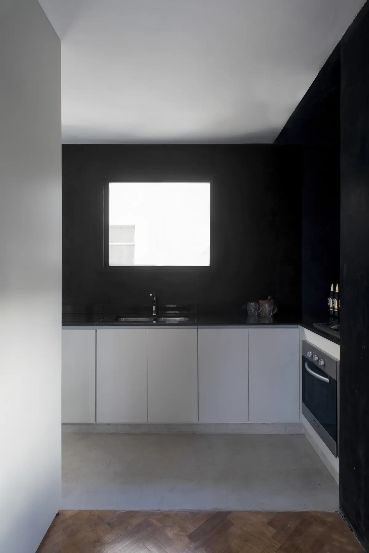 Cocina minimalista blanca y negra con ventanal iluminado — proyecto Departamento Barrancas, por Ekaterina Kunzel Arquitecta, en Belgrano