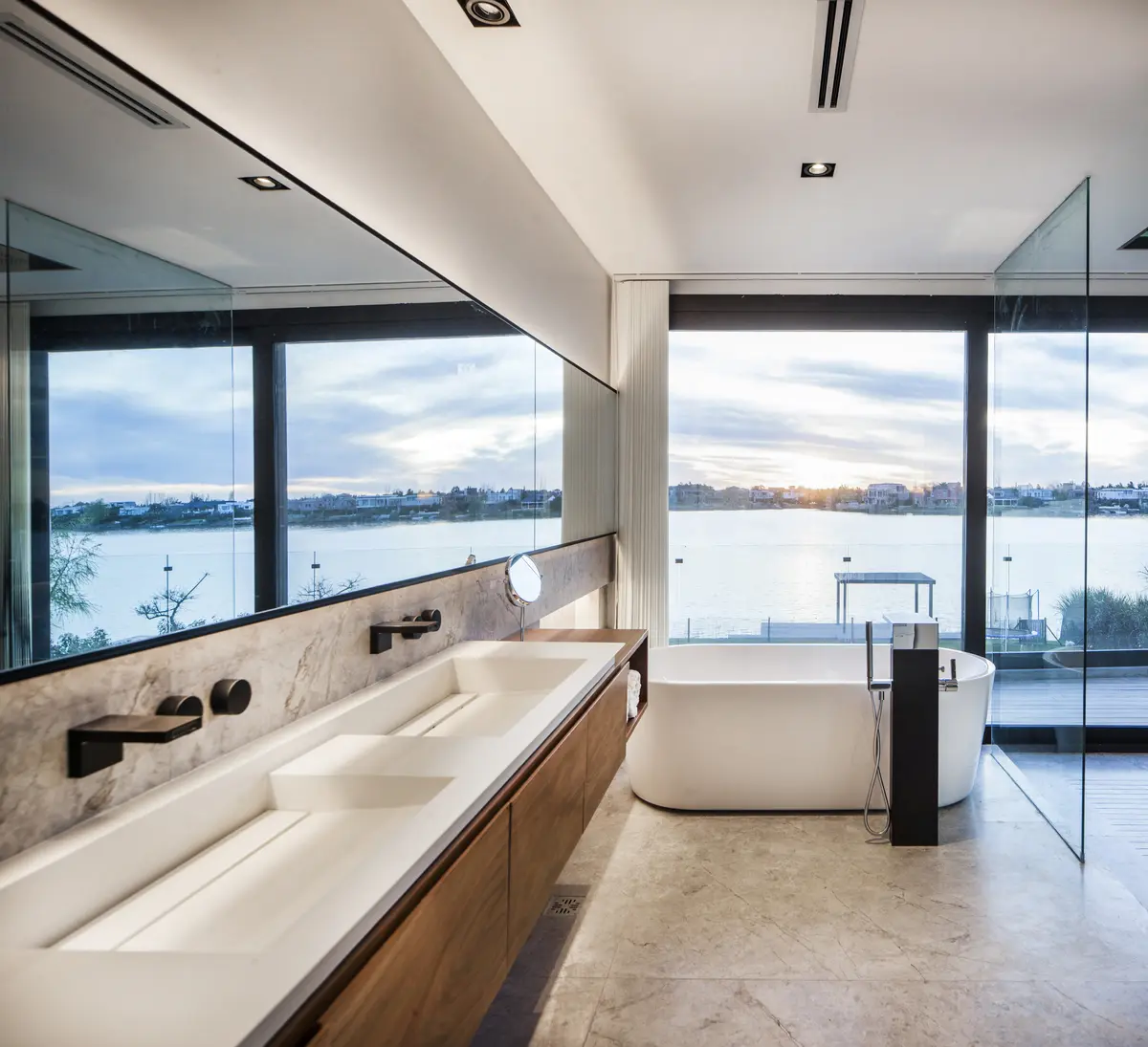 Banheiro moderno com vista para o mar, pia dupla e banheira de imersão — projeto Casa Buddha, por Estudio Simbiosis
