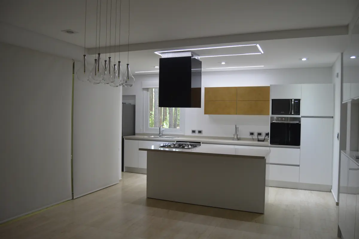 Cocina moderna abierta con isla central y campana negra — proyecto PINAMAR NORTE, por LADAGA-RUARTE-Pinamar, en Pinamar