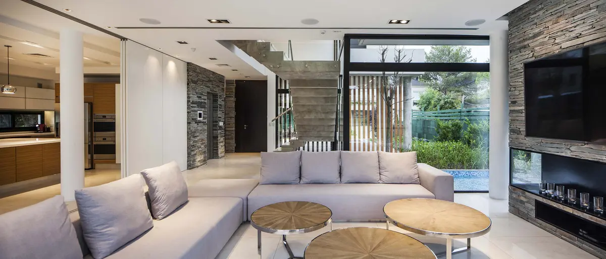 Sala moderna com parede de pedra e janelas grandes para jardim — projeto Simpleza moderna, por Apaarquitectura
