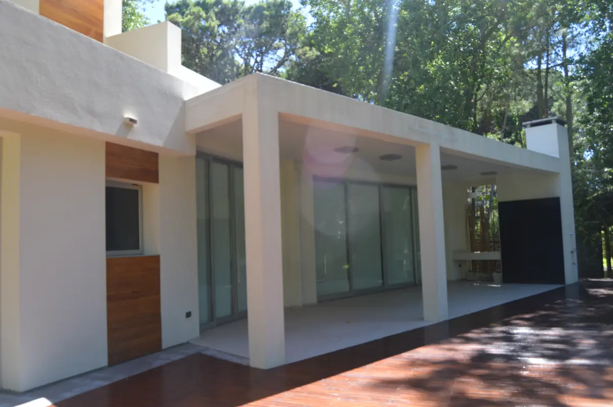 Fachada moderna com pátio coberto e detalhes em madeira — projeto CARILO - Boyero, por LADAGA-RUARTE-Pinamar, em Cariló
