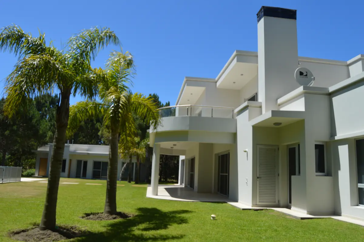 Fachada moderna estilo mediterrâneo com palmeiras — projeto LA HERRADURA - Boulevard I, por LADAGA-RUARTE-Pinamar, em Pinamar