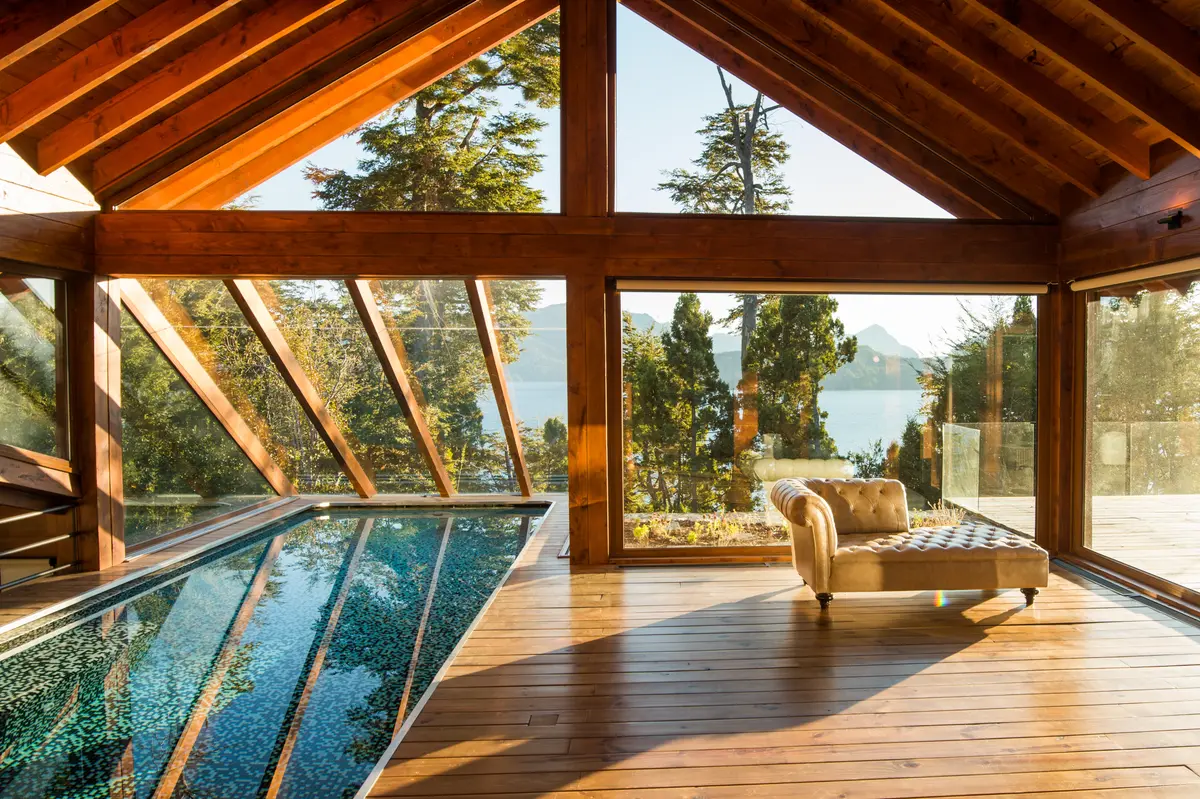 Pileta interior-exterior con techo de madera y vista al lago — proyecto Casa Villa La Angostura, por Sidoni & Asociados, en Villa La Angostura