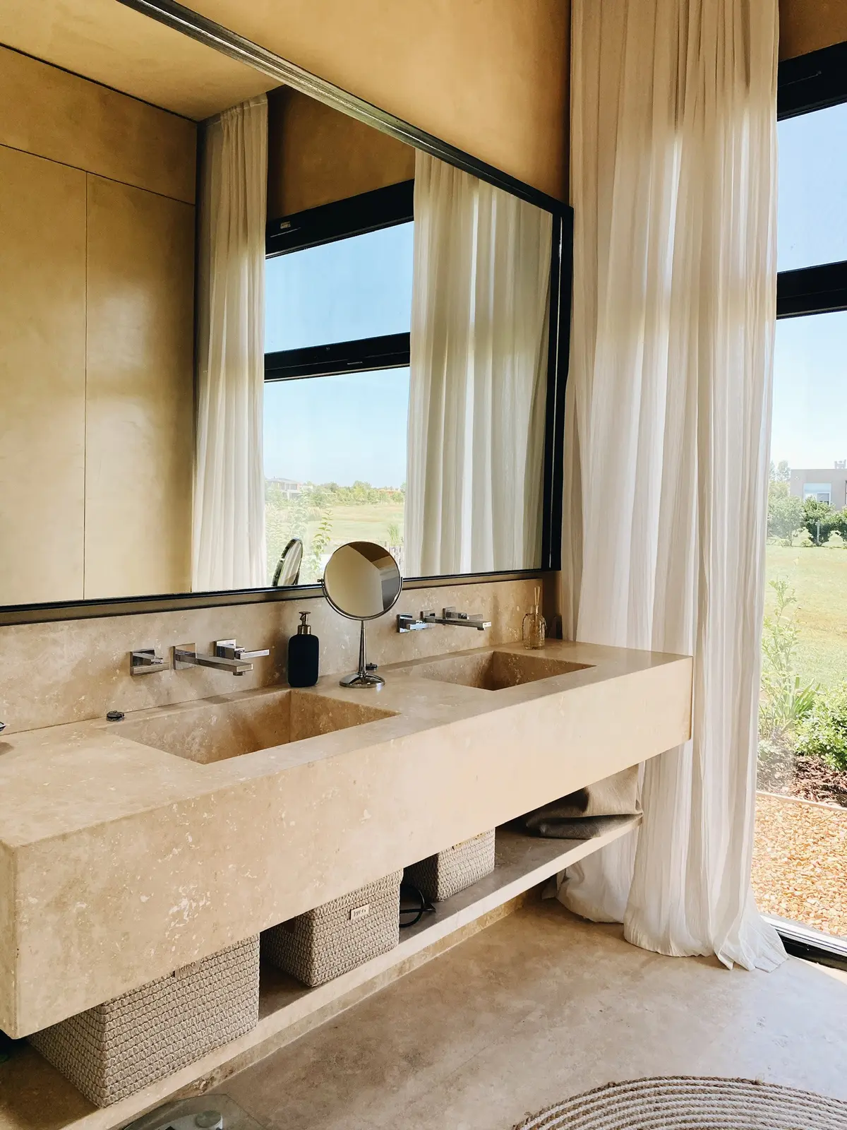 Baño moderno con doble bacha de piedra y gran ventanal — proyecto Pilará 38, por Detry Miguens Arquitectura, en Pilará