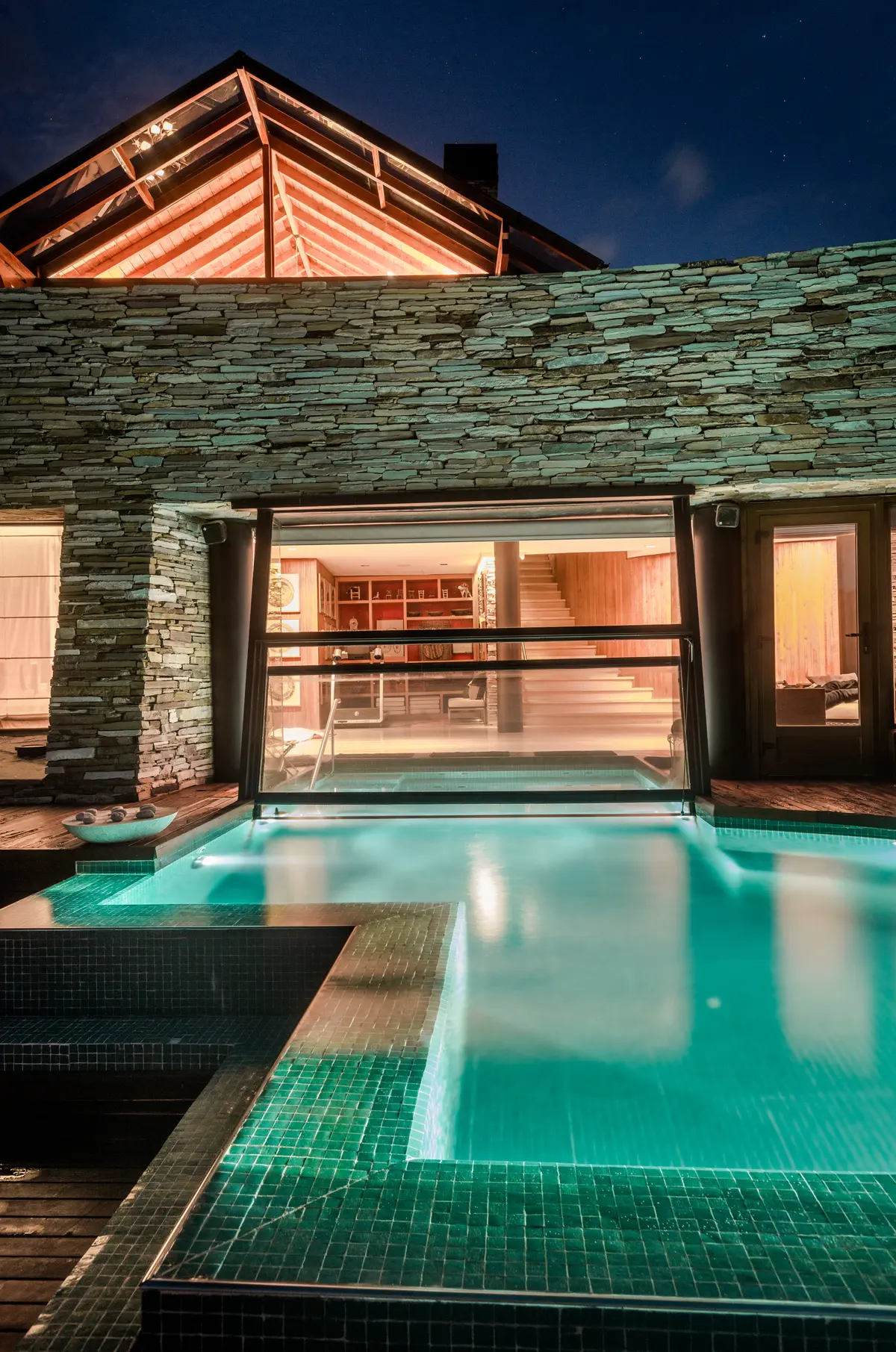 Piscina interior moderna con fachada de piedra y pared de vidrio — proyecto Casa Villa La Angostura 2, por Sidoni & Asociados, en Villa La Angostura