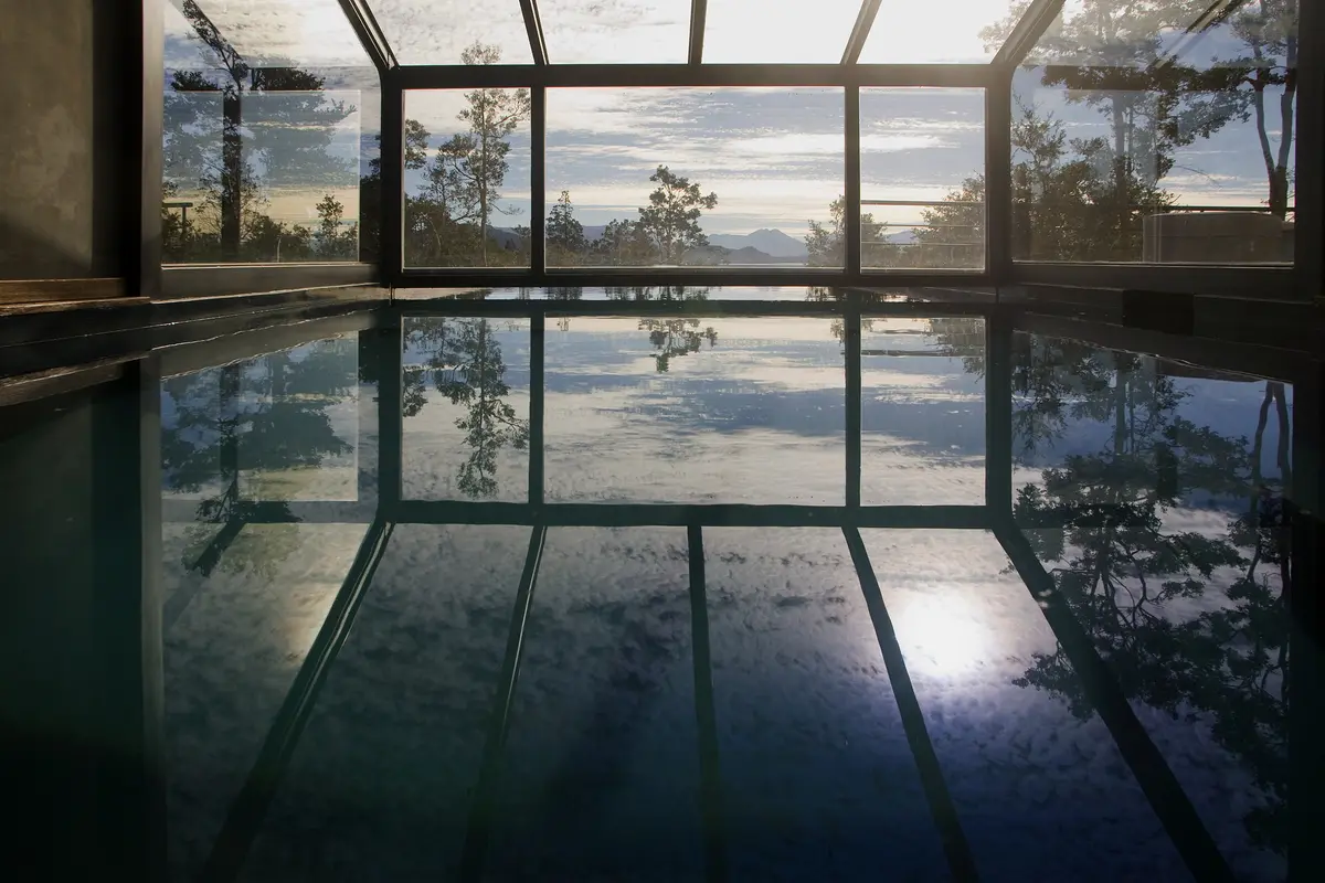 piscina interior con techo vidriado y vista a la montaña — proyecto Casa Muelle de Piedra, por Sidoni & Asociados, en Villa La Angostura