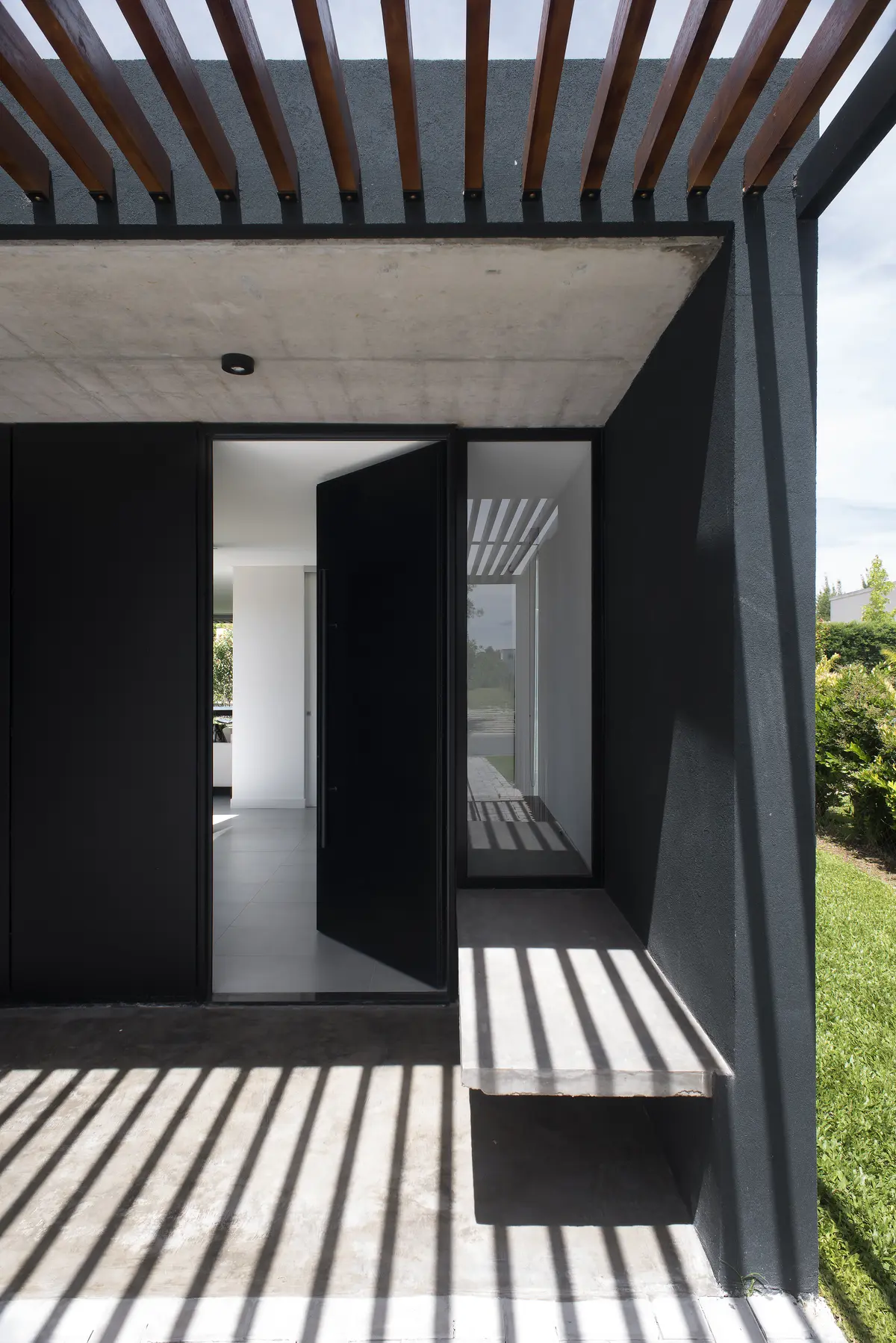 fachada moderna com porta pivotante preta e pergolado — projeto Casa 2LH, por Luciano Kruk