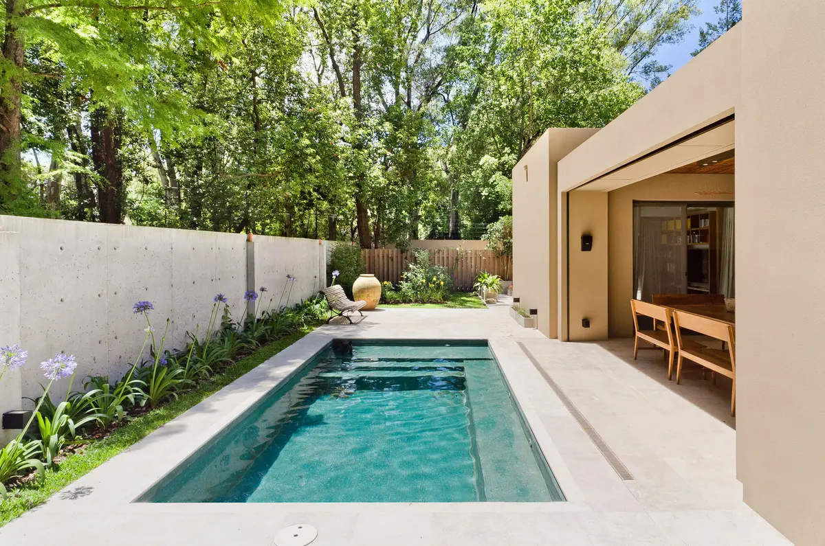piscina moderna con fachada de hormigón y vegetación exuberante — proyecto Casa P, por Estudio Dado, en San Isidro