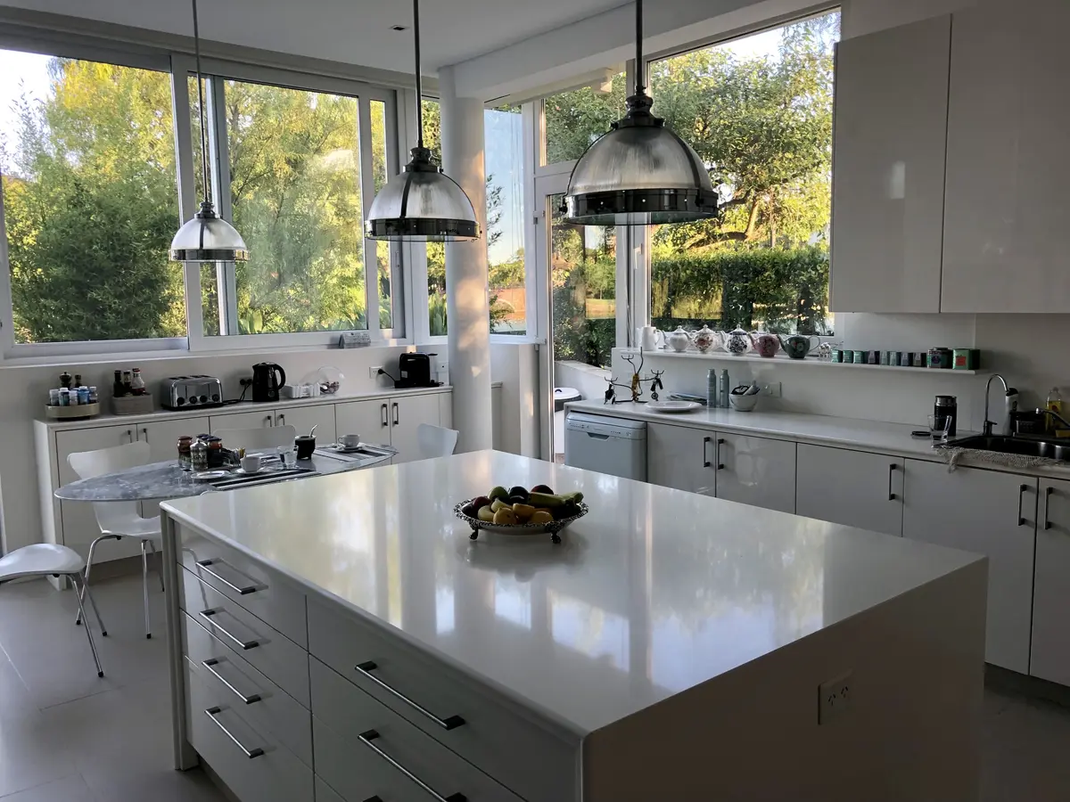 Cocina moderna minimalista con isla blanca y ventanales amplios — proyecto CASA LAGUNA, por Estudio Xime Fontan Balestra, en Tigre